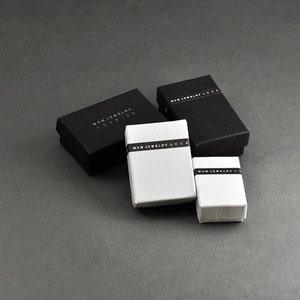 May include: Four small boxes, two black and two white, with the text "MXM JEWELRY COLLECTION" printed on the black boxes and "MXM JEWELRY LONDON" printed on the white boxes.