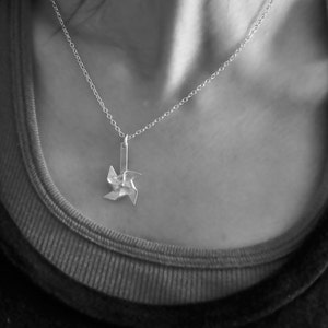 May include: A silver necklace with a delicate silver pinwheel pendant.
