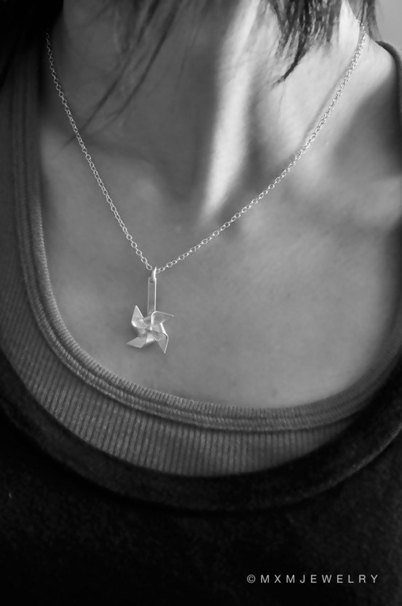 May include: A silver necklace with a delicate silver pinwheel pendant.