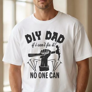 Könnte beinhalten: Weißes T-Shirt mit dem Text "DIY DAD if I can't fix it! NO ONE CAN" in Schwarz. Die Grafik zeigt eine Hand, die einen Hammer und Nägel hält. Das Shirt ist ein Freizeitartikel.