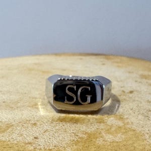 May include: A silver signet ring with the initials "SG" engraved on the top.