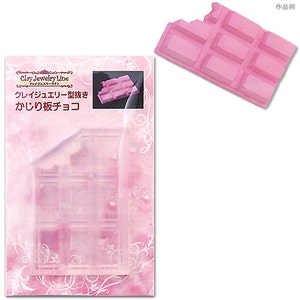 Può includere: Uno stampo in plastica rosa per fare una barretta di cioccolato. Lo stampo ha la forma di una barretta di cioccolato con un morso. Lo stampo è mostrato accanto a una barretta di cioccolato finita realizzata con lo stampo.