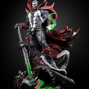 May include: A detailed Spawn collectible statue featuring a muscular figure in a grey and black suit with a flowing red cape, a skull belt, and spiked wrist and leg guards. The figure holds a large sword and stands atop a creature with green slime.
