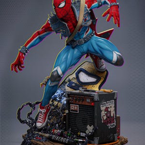 Puede incluir: Una estatua dinámica de Spider-Man en estilo punk rock, con un traje rojo y azul con púas y un chaleco vaquero. Está posando con una guitarra, de pie sobre una base con un amplificador que tiene el texto "WANTED DEAD OR ALIVE".