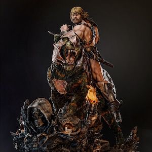 May include: A detailed statue of a muscular figure riding a large, armored beast. The figure, with blonde hair and a determined expression, holds a sword. The beast has green and brown fur and a menacing open mouth. A torch and skull-like structure are at the base.