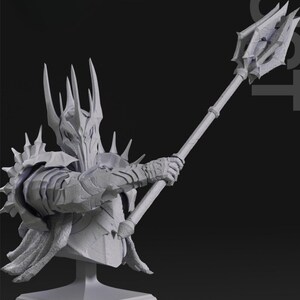 Może przedstawiać: Szara, tr&oacute;jwymiarowa, wydrukowana figura przedstawiająca postać fantasy w koronie i zbroi, trzymająca laskę z kolczastym zakończeniem. Figura stoi na kwadratowej podstawie.