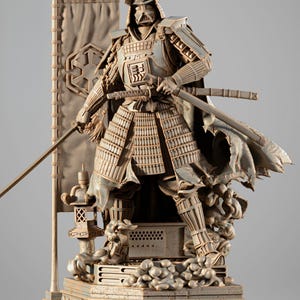 Op de afbeelding: Een gedetailleerd beeldhouwwerk van een samoerai-krijger in harnas, met twee zwaarden. De figuur staat in een dynamische pose, met een cape en een banner met een symbool. Het beeldhouwwerk is in grijstinten en beige, met ingewikkelde details.