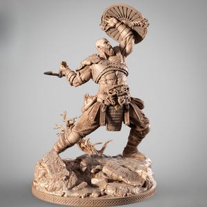 May include: A detailed, brown figurine of a warrior in a dynamic pose, holding a shield and a weapon. The figure is on a rocky base with carved inscriptions. The warrior is clad in armour and has a beard. The overall theme is a historical or fantasy character.