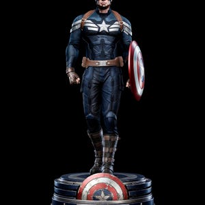 Può includere: Statua di Captain America in posa dinamica, vestito con un costume blu e bianco con un'emblema a stella. La figura tiene uno scudo rosso, bianco e blu. La base presenta lo scudo di Captain America e il testo "CAPTAIN AMERICA THE WINTER SOLDIER."