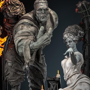 Pode incluir: Uma estátua detalhada do monstro de Frankenstein e sua noiva. O monstro é cinza com cicatrizes costuradas, vestindo roupas esfarrapadas. A noiva está em um vestido branco, com uma tez pálida e cicatrizes costuradas. A cena inclui velas e elementos arquitetônicos góticos.