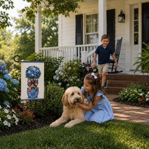 Puede incluir: Una bandera de jardín con un diseño floral azul y blanco y un lazo rojo, blanco y azul. Una niña y un niño jugando afuera con un perro golden doodle frente a una casa blanca con contraventanas negras.