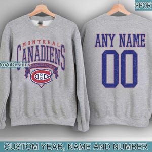 Könnte beinhalten: Ein meliertes graues Sweatshirt mit dem Logo der Montreal Canadiens auf der Vorderseite und dem Text "ANY NAME" und der Nummer "00" auf der Rückseite. Das Sweatshirt enthält den Text "CUSTOM YEAR, NAME AND NUMBER".