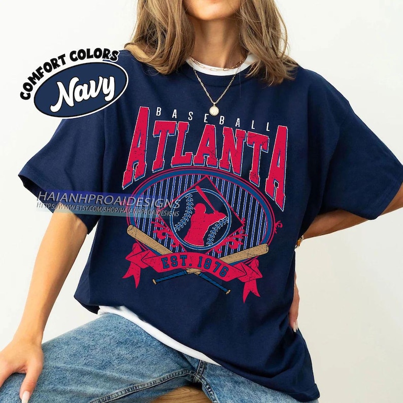 May include: A navy blue t-shirt with a white underlay. The shirt features a vintage-style baseball graphic with the text "BASEBALL ATLANTA EST. 1976" in red and white.