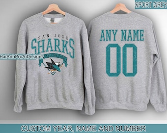 May include: Grey sweatshirt featuring the text "SAN JOSE SHARKS ESTABLISHED 1991" on the front. The back of the sweatshirt has the text "ANY NAME" above the number "00". The bottom of the sweatshirt says "CUSTOM YEAR, NAME AND NUMBER".