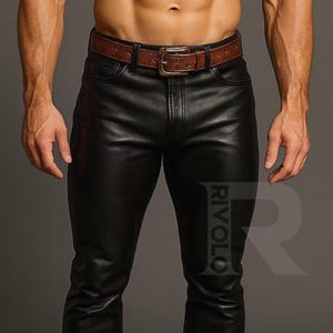 May include: Black leather trousers with a brown leather belt. The trousers have a classic five-pocket design and a straight leg. The belt has a silver buckle. The word "RIVOLO" is printed on the trousers.