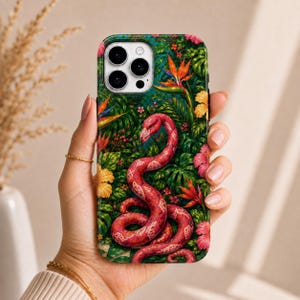 May include: A smartphone case featuring a vibrant tropical design with a pink flamingo-headed snake coiled amidst lush green foliage, orange bird of paradise flowers, and yellow and pink hibiscus blossoms against a dark green jungle background.