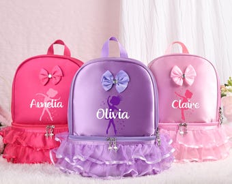 Op de afbeelding: Drie gepersonaliseerde ballerina rugzakken met een tule rok. De rugzakken zijn roze, paars en lichtroze. Elke rugzak heeft een strik en een ballerina silhouet met de naam "Amelia", "Olivia" en "Claire" gedrukt op de voorkant.