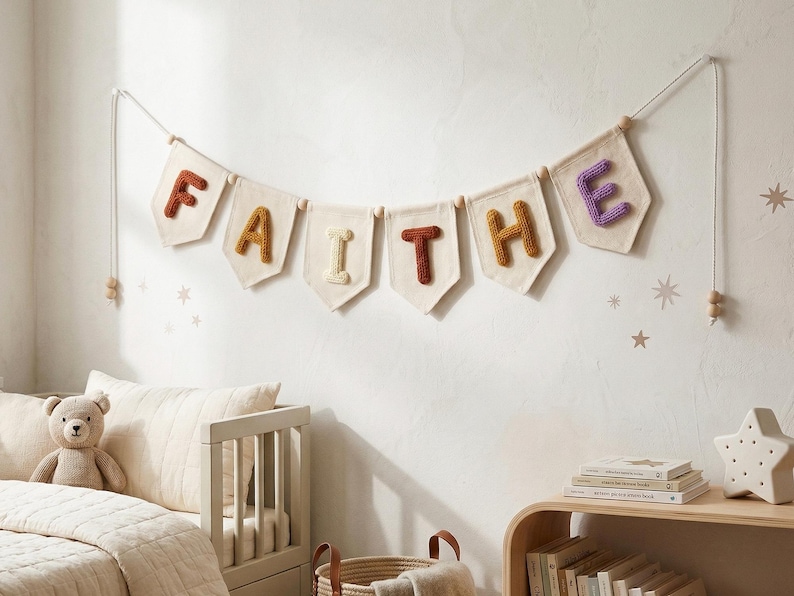Puede incluir: Un cartel con la palabra "FAITHE" cuelga de una pared. Cada letra es de un color diferente, con un fondo color crema. El cartel est&aacute; ensartado en un cord&oacute;n blanco con cuentas de madera. La habitaci&oacute;n tiene una paleta de colores neutros.