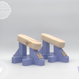 Puede incluir: Dos parallettes de gimnasia de madera, con bases azul claro y soportes para las manos de madera natural. Las parallettes tienen un logotipo hecho a mano con amor y un logotipo de entrega gratuita.