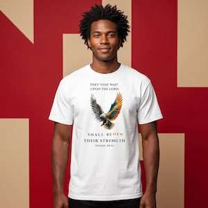 Könnte beinhalten: Ein weißes T-Shirt mit kurzen Ärmeln und einer Adlergrafik, bei der ein Flügel in Graustufen und der andere in leuchtenden Farben dargestellt ist. Der Text lautet: THEY THAT WAIT UPON THE LORD SHALL RENEW THEIR STRENGTH ISAIAH 40:31.