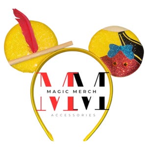 May include: A yellow headband with mouse ears. One ear features a red feather and a wooden stick, the other ear has a glittery red face with a blue bow. The headband has the text "MAGIC MERCH ACCESSORIES".