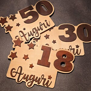 Biglietto di auguri in legno dipinto a mano con scritte in rilievo tono su tono.