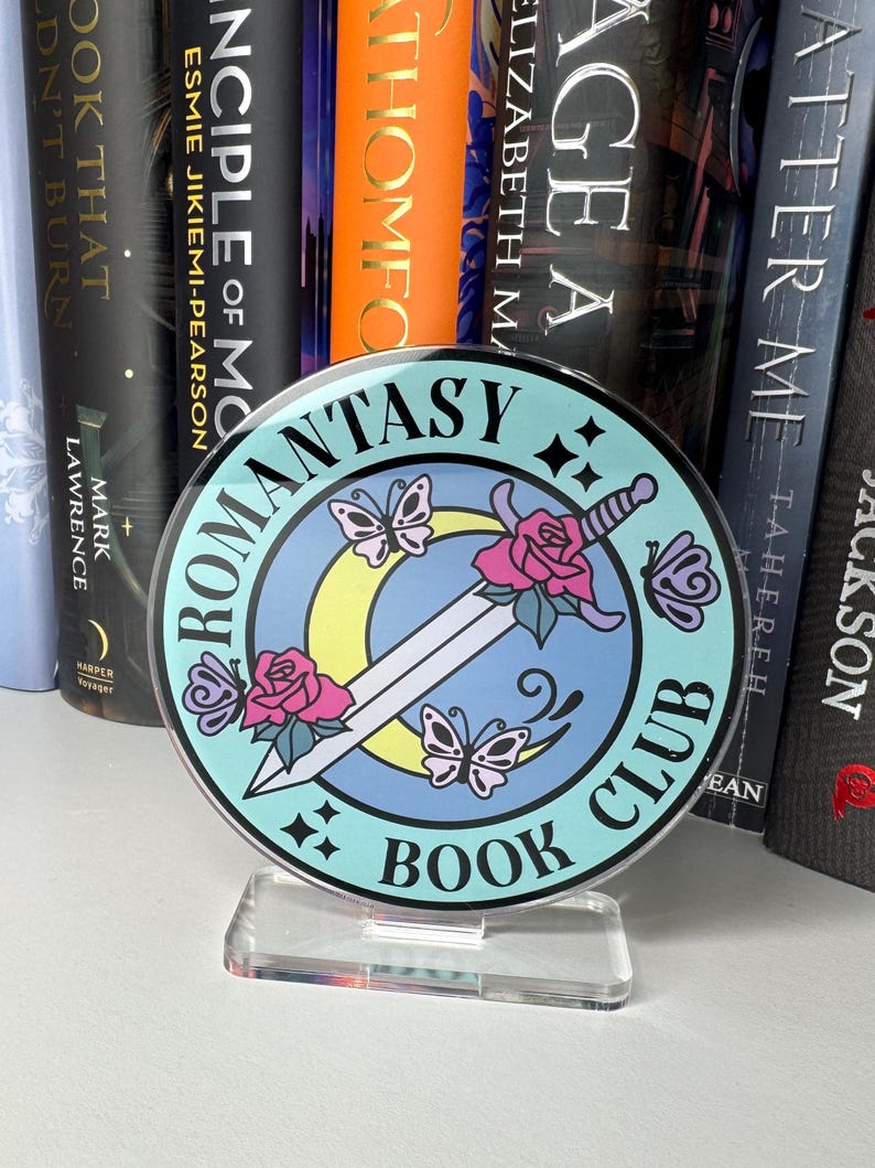 May include: A round, blue and white book club sign with a sword, flowers, and butterflies. The sign says "Romance Fantasy Book Club".