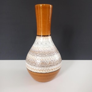 May include: A decorative ceramic vase with a brown top and base, and a white and silver patterned body. The vase has a bulbous shape with a narrow neck, and stands approximately 8 inches tall.