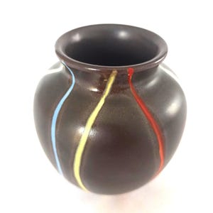 May include: A small, brown ceramic vase with a rounded body and a dark interior. The vase is adorned with vertical stripes of blue, yellow, and red paint. The vase is a decorative item.