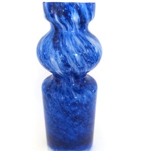 Puede incluir: Un jarrón de vidrio azul y blanco con remolinos. Tiene una base cilíndrica y una sección media redondeada, estrechándose hacia la parte superior. La base es blanca, que se funde en un azul profundo. Objeto decorativo.