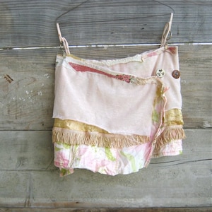 May include: A pink and white layered skirt with a gold trim and fringe. The skirt is made of different fabrics and has a vintage look.