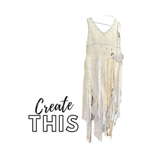 Puede incluir: Vestido sin mangas color crema con escote en V, adornado con pequeños tachuelas plateadas y cintas decorativas. El vestido presenta una falda en capas con varias texturas y longitudes de tela. Las palabras "Create THIS" están escritas en guión negro.