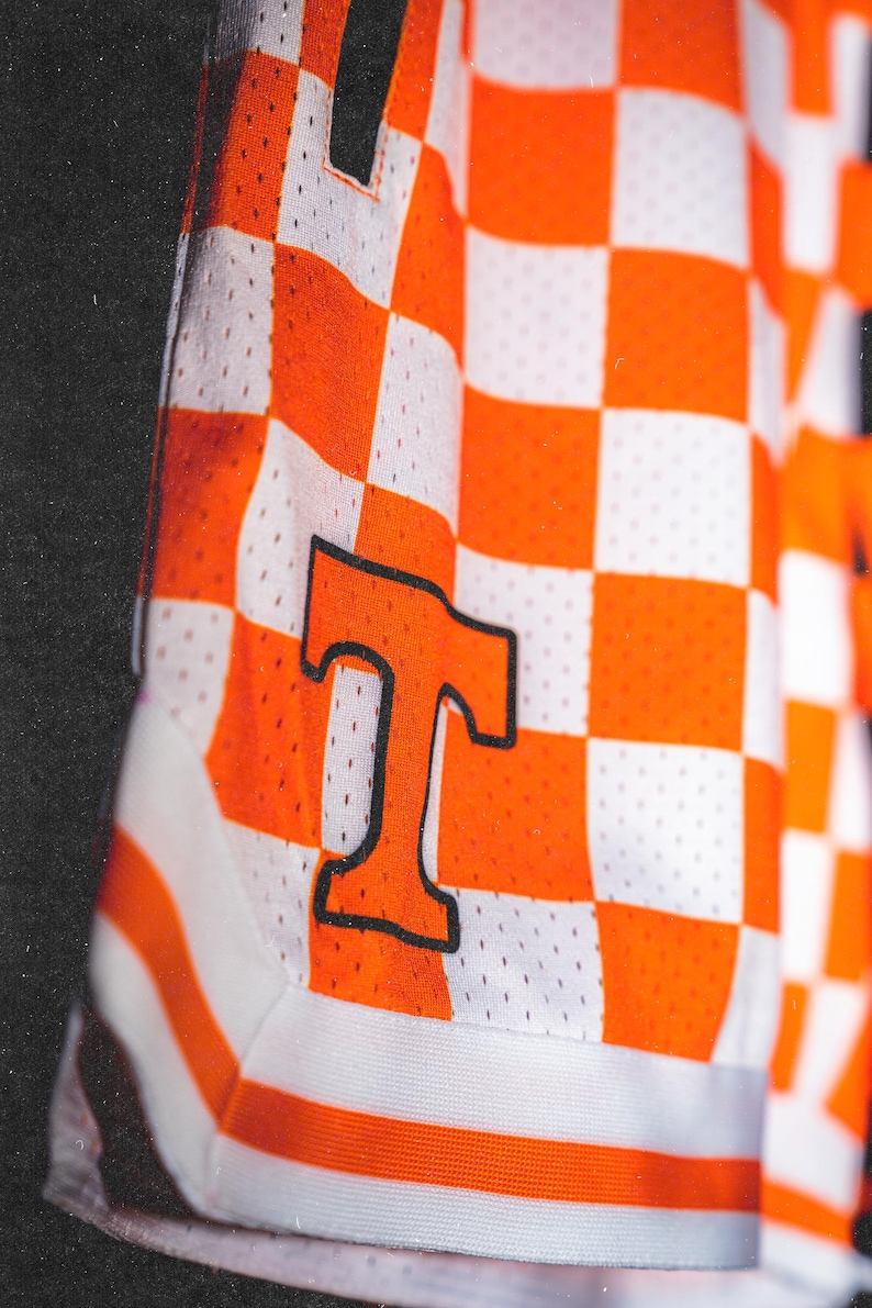 May include: Orange and white checkered basketball shorts with a black "T" on the side.