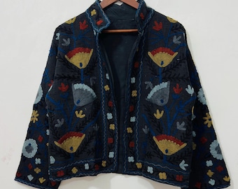 May include: A dark charcoal gray jacket featuring an open front and long sleeves. The garment is decorated with intricate floral embroidery in shades of mustard yellow, light blue, and red, covering the front panels and the sleeves.