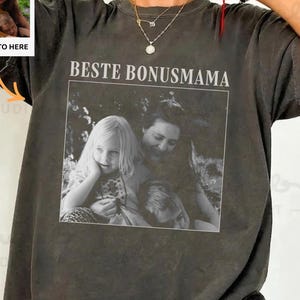 Könnte beinhalten: Dunkelgraues T-Shirt mit einem Schwarz-Weiß-Foto und dem Text "BESTE BONUSMAMA". Ein kleines Foto mit dem Text "YOUR PHOTO HERE" befindet sich in der oberen linken Ecke. Das Shirt hat eine lockere Passform.