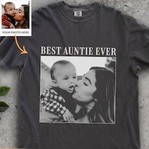 Könnte beinhalten: Pfefferfarbenes T-Shirt mit dem Text "BEST AUNTIE EVER" über einem Schwarz-Weiß-Foto eines Babys, das geküsst wird. Ein kleineres Foto mit dem Text "YOUR PHOTO HERE" befindet sich oben links. Das Shirt hat einen Rundhalsausschnitt.