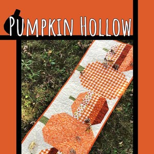 May include: A quilted table runner featuring a design of three pumpkins in orange, brown, and white checkered fabric. The runner is on a bed of green grass with fallen leaves. The text "Pumpkin Hollow" is at the top of the image. The text "Tricia Lynn Maloney Orphan Quilt Designs For Villa Rosa Designs" is at the bottom of the image.