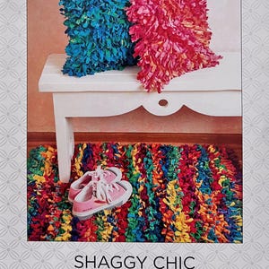 May include: A product image featuring a blue and pink shaggy pillow set, a matching rug, and pink sneakers. The pillows and rug have a textured, fringed appearance. The text "ATKINSON DESIGNS" and "SHAGGY CHIC" are visible.