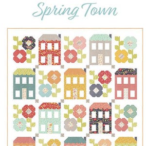 May include: A colorful quilt pattern titled "Spring Town" featuring patchwork houses and floral designs. The houses are in various colors, and the flowers have detailed patterns. The design is labeled "Layer Cake Friendly" and includes the designer's name.