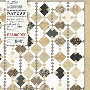 May include: A quilt pattern with a geometric design of diamond shapes in beige, brown, and black. The pattern is by Audrey Tanke for Basicgrey, labelled "Bijou Breeze" and "PAT085". The design features a variety of patterns.