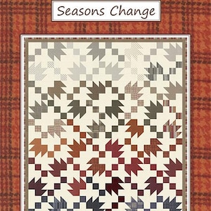 May include: A quilt with a leaf pattern in shades of brown, red, and gray, set against a cream background. The quilt is framed by a white border and a plaid pattern in shades of orange and brown. The text "Seasons Change" and "by Coach House Designs" are displayed.