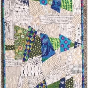 May include: A patchwork quilt with a white background and four colorful Christmas trees. The trees are made of different fabrics with green, blue, purple, and white patterns. The quilt is framed with a blue border.