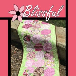 Peut inclure: Une courtepointe rectangulaire composée d'un patchwork d'hexagones en tissu rose, vert et marron à motifs floraux. La courtepointe présente une bordure vert clair avec des motifs matelassés en spirale et un bord marron foncé. Le texte Blissful, Tricia Lynn Maloney, Orphan Quilt Designs et For Villa Rosa Designs figure sur l'image.