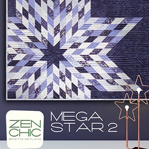May include: A framed quilt with a large star design in shades of blue, lavender, and white. The star is composed of diamond-shaped fabric pieces. The quilt is labeled "MEGA STAR 2" with the "ZEN CHIC" logo. A decorative star-shaped object is in the foreground.