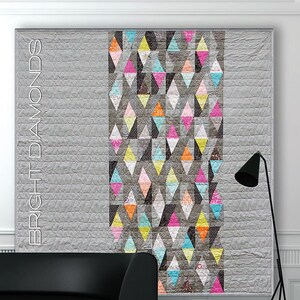 May include: A rectangular quilt featuring a large solid gray section and a central vertical panel composed of diamond-shaped fabric pieces in bright pink, orange, yellow, and teal. The text BRIGHT DIAMONDS is printed vertically on the left side.
