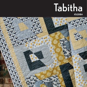 May include: A colorful quilt with a geometric pattern in shades of gray, yellow, and black. The quilt features the name "Tabitha" at the top and the words "Fat Quarter Friendly!" at the bottom. The quilt is made by Swirly Girls.