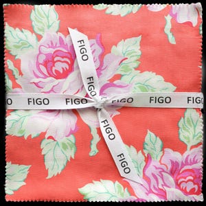 May include: A square stack of fabric squares with a floral pattern in shades of pink, white, and green on a coral background. The fabric is tied with a white ribbon printed with the word "FIGO".