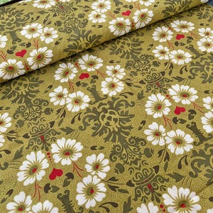 May include: Close-up of a fabric with a repeating floral pattern. White daisy-like flowers with red centers and small red hearts are scattered across a light olive-green background. Dark green ornate scrollwork adds detail to the design.