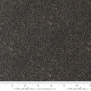 May include: Dark fabric with a repeating floral pattern in a light beige colour. The design features swirling vines, leaves, and small flower shapes. The fabric has a ruler along the bottom with the word "moda" printed on it.