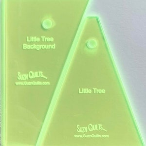 May include: Two green acrylic quilting templates for making a little tree block. The larger template is labeled "Little Tree Background" and the smaller template is labeled "Little Tree". Both templates have the Suzn Quilts logo and website address.